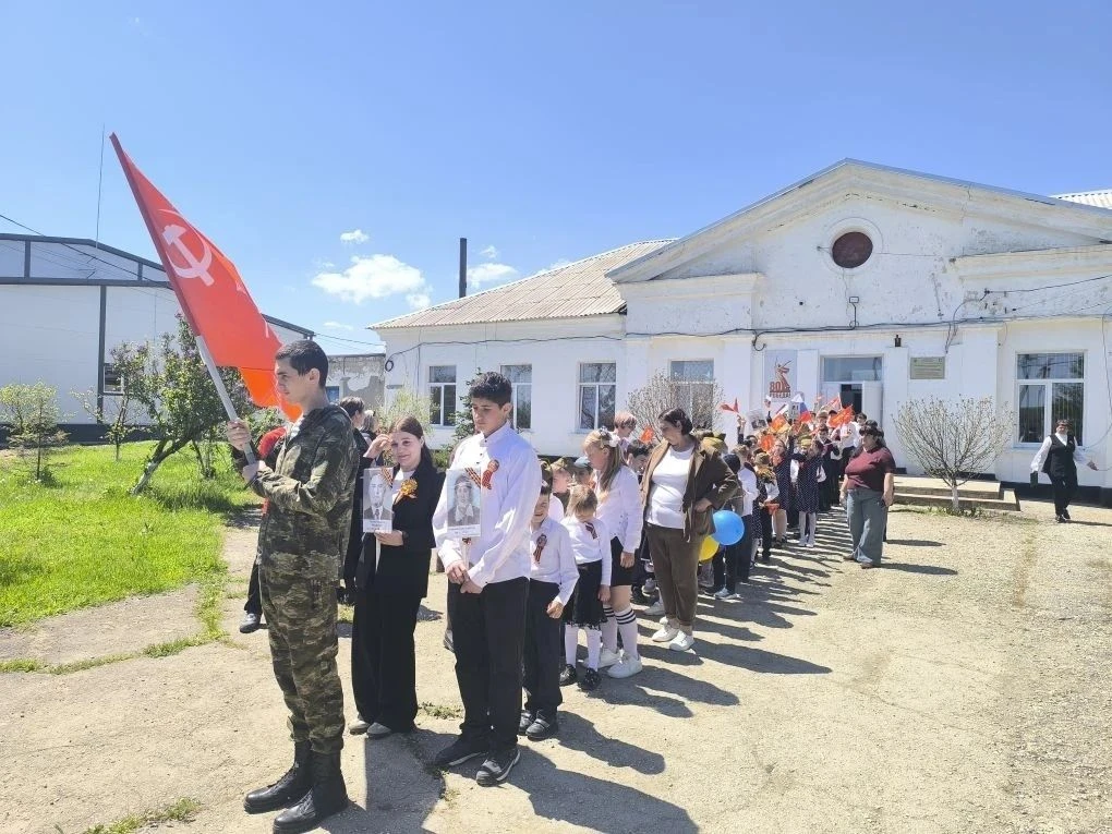 Бессмертный полк шагает по планете,
Несут портреты взрослые и дети.
Шагает с нами, выстроившись в ря