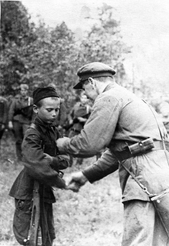 30 июля 1942 года. Командир партизанского отряда вручает медаль «За отвагу» юному партизану-разведчи