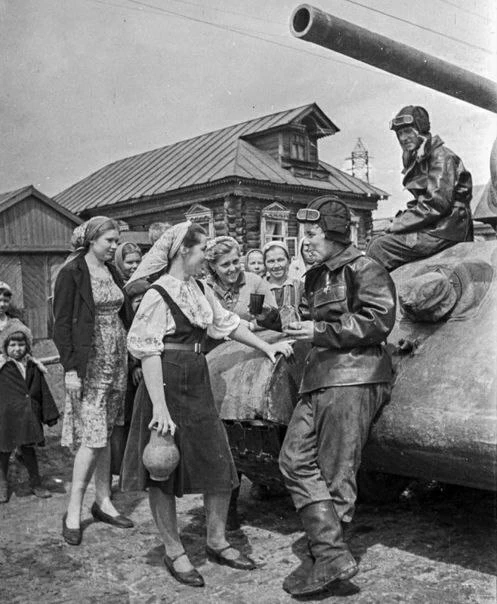 Встреча с бойцами. Девушки угощают экипаж советского танка Т-34 на сельской улице.