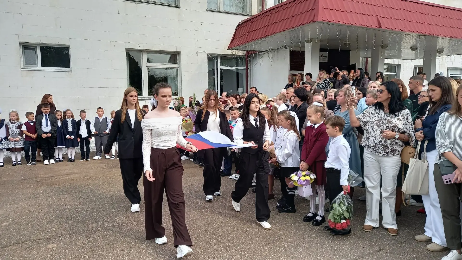 Участницы всероссийского конкурса "Большая перемена" поднимают флаг России на школьной ...