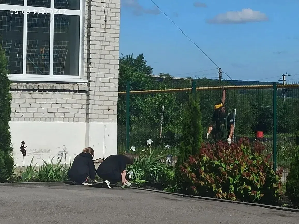 Девушки из трудовой бригады наводят порядок на школьной территории: пропалывают клумбы, сажают цветы