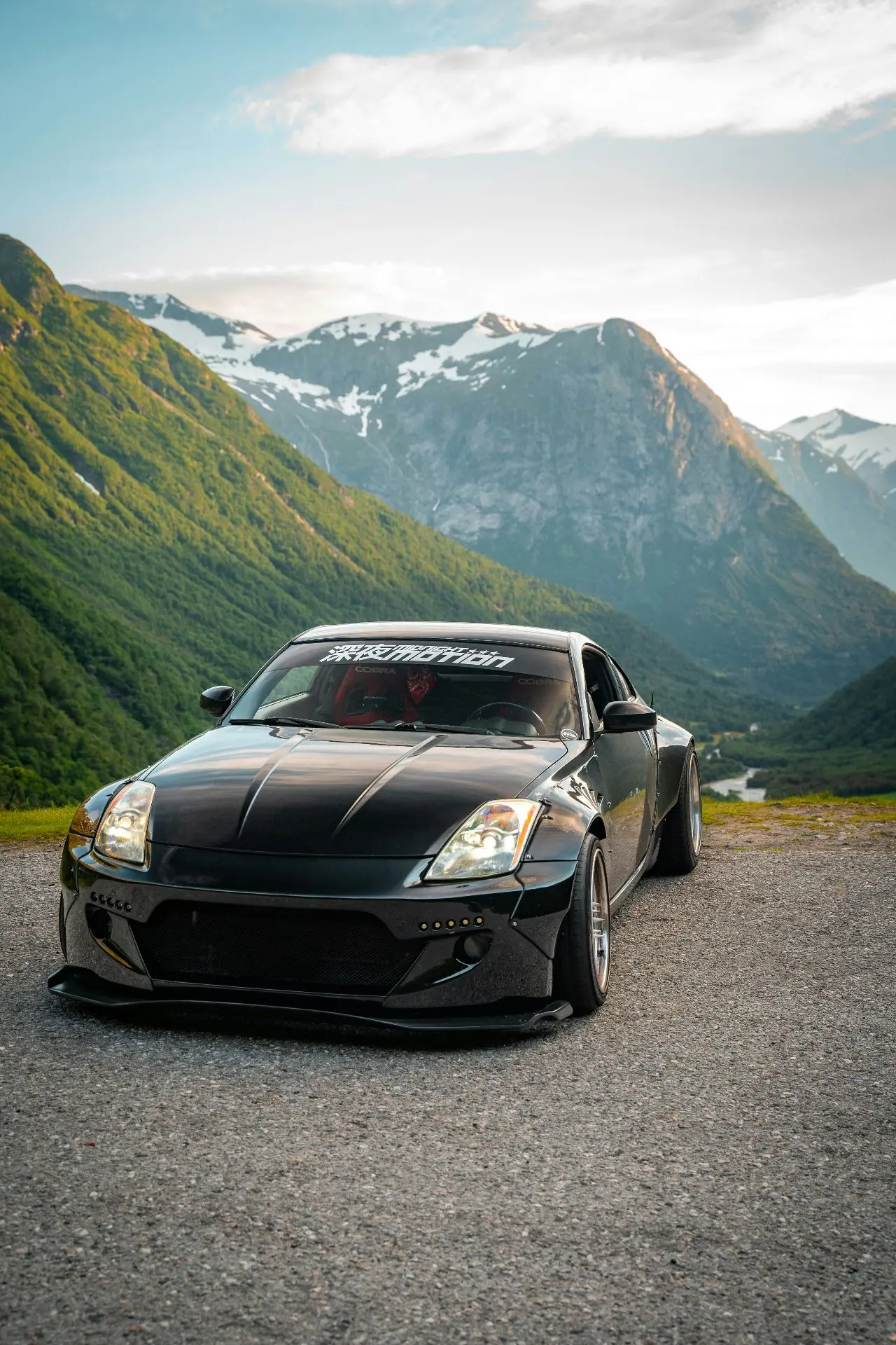 Чёрный Nissan 350Z на фоне норвежских гор. Низкий силуэт, широкая посадка и тёмный кузо...