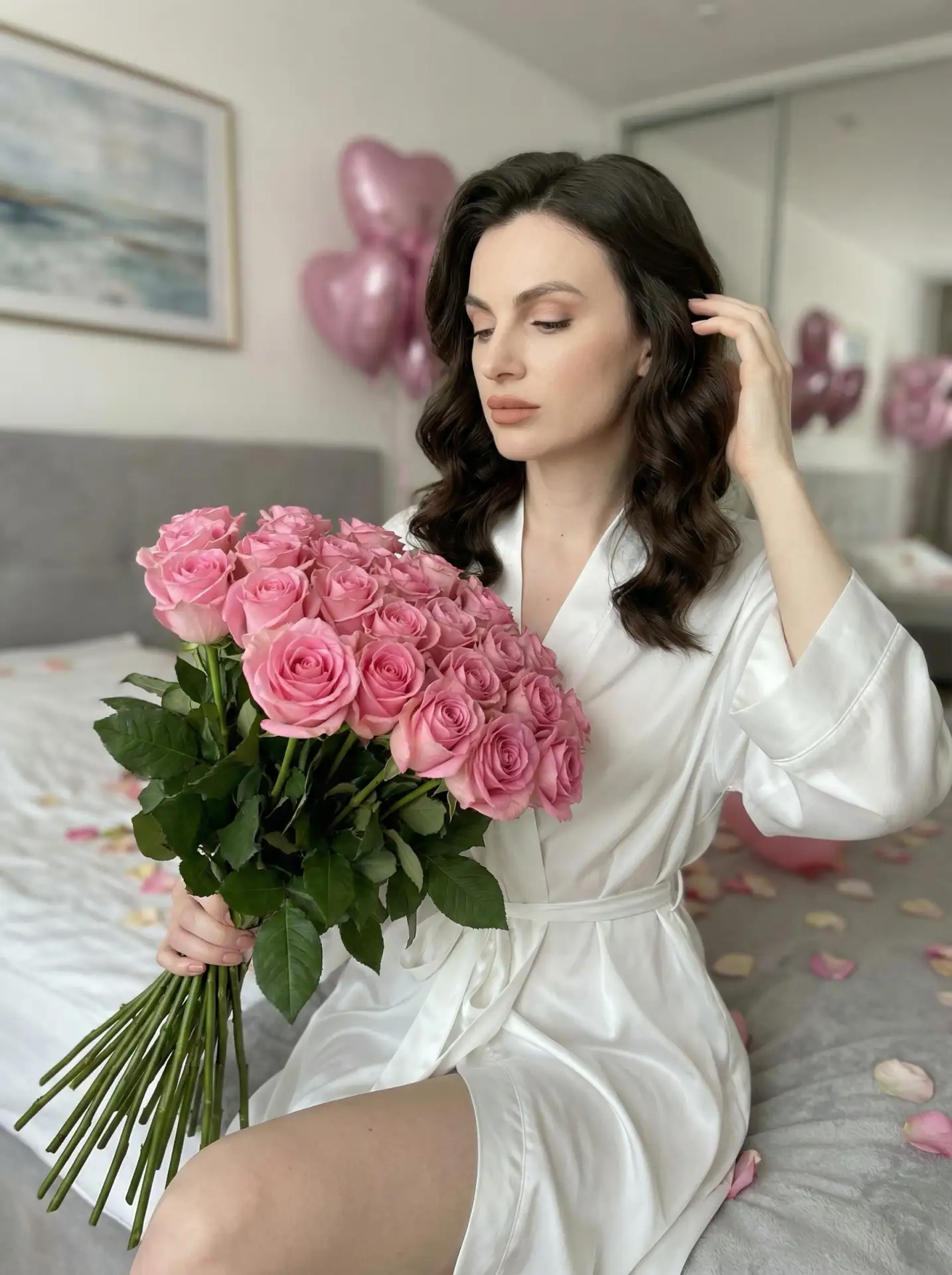 🖼 Woman is sitting on a bed in a bright bedroom