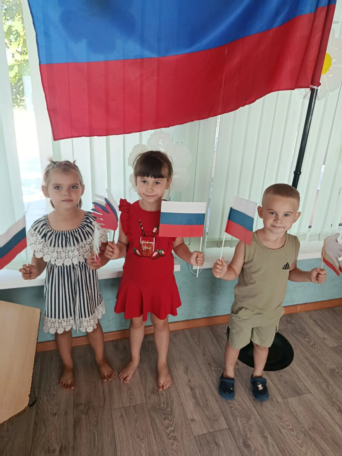 В детских ручках — маленький флажок.