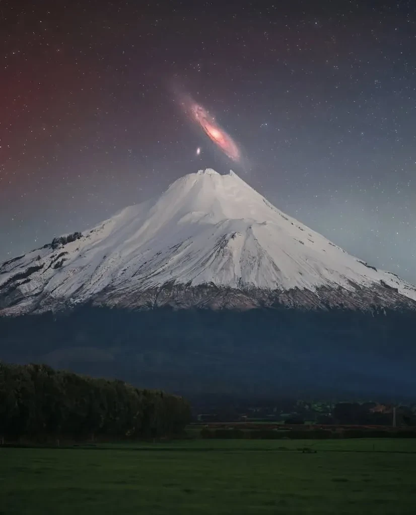 На этой фотографии запечатлена Галактика Андромеды (M31), сияющая прямо над заснеженным пиком вулкан