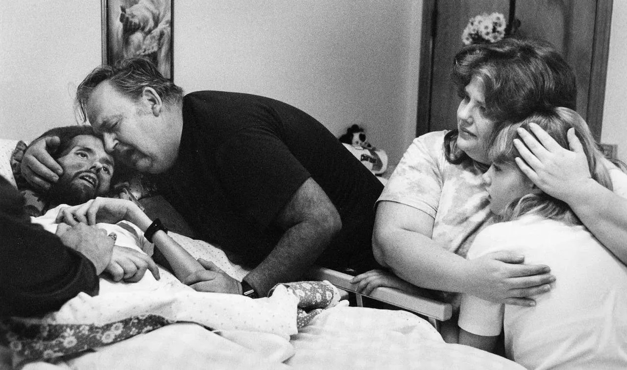 Отец утешает своего сына Дэвида Кирби на смертном одре в Огайо, 1989 год.  Эта фотография считается 