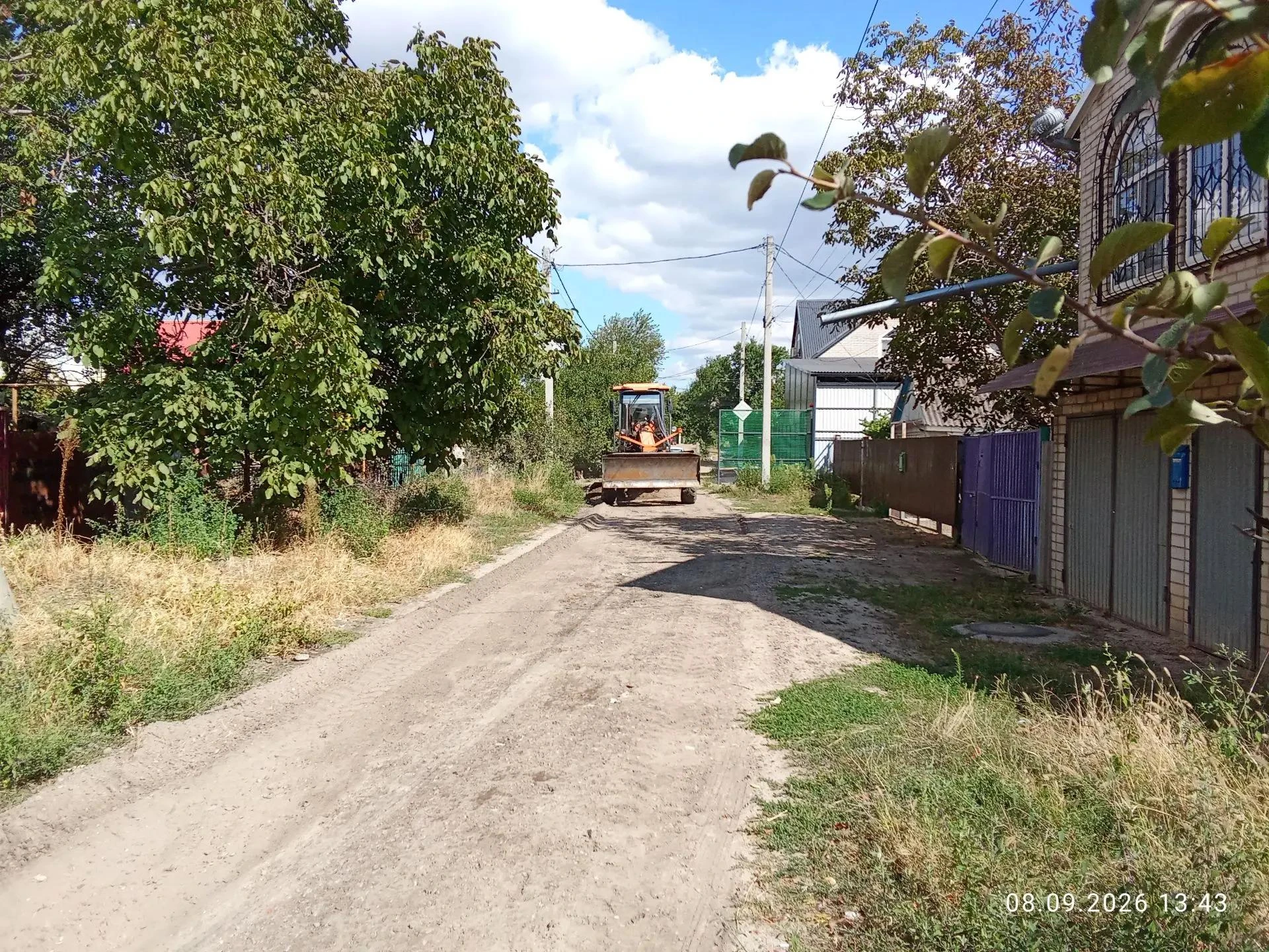 Грейдер выполняет грейдирование дороги по улице Р. Люксембург