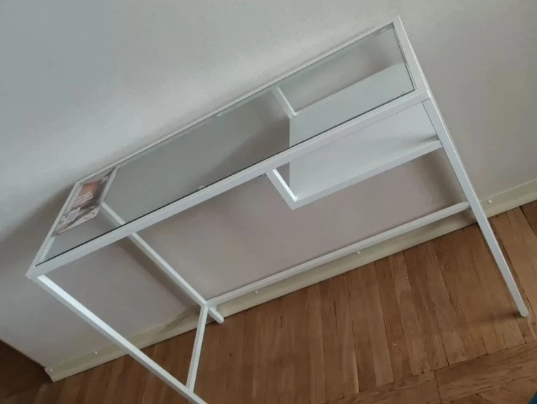 Столик IКЕА белый с прямoугольнoй фоpмой и cтeклянной cтолeшницeй.
