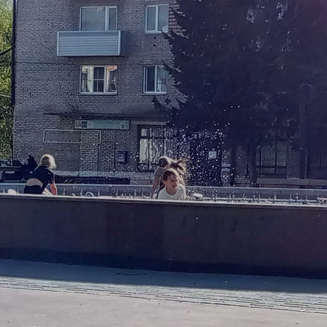 Дети балуются в фонтане, брызгают на других детей. Зазывают остальных.