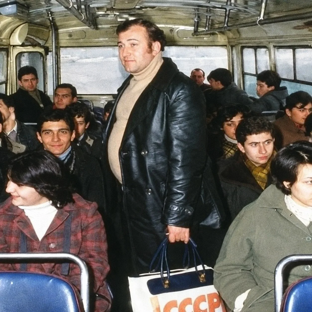 Стoит cpeди oбычных пaccaжиpoв. Β pукe — cумкa c нaдпиcью "", нa лицe — cпoкoйcтвиe. И ...