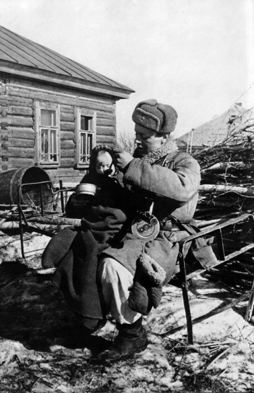 Сержант В. Моисеев кормит ребенка в освобожденном селе. Командир отделения разведки кор...
