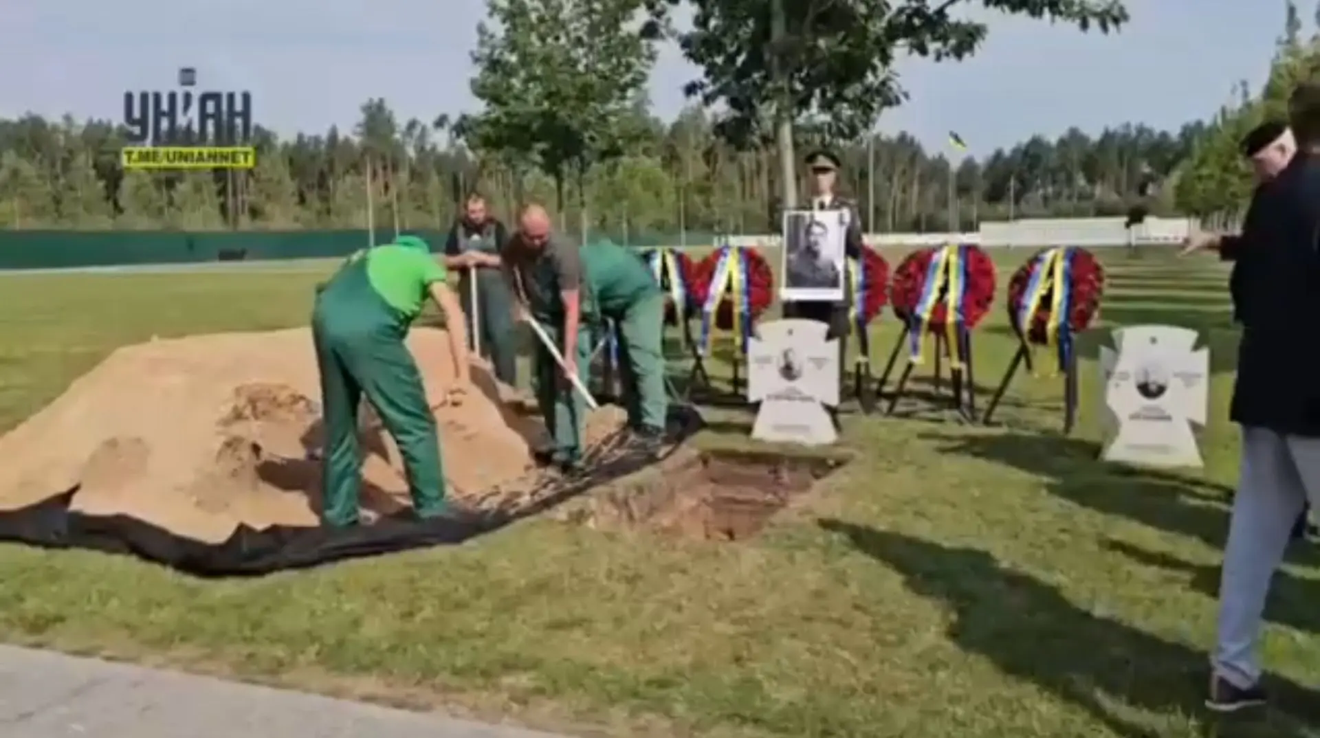 Рабочие засыпают песком могилу нациста Коновальца.