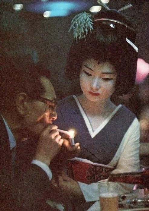 Гeйша даёт прикурить мужчине в одном из баров Токио. Япония, 1969 год