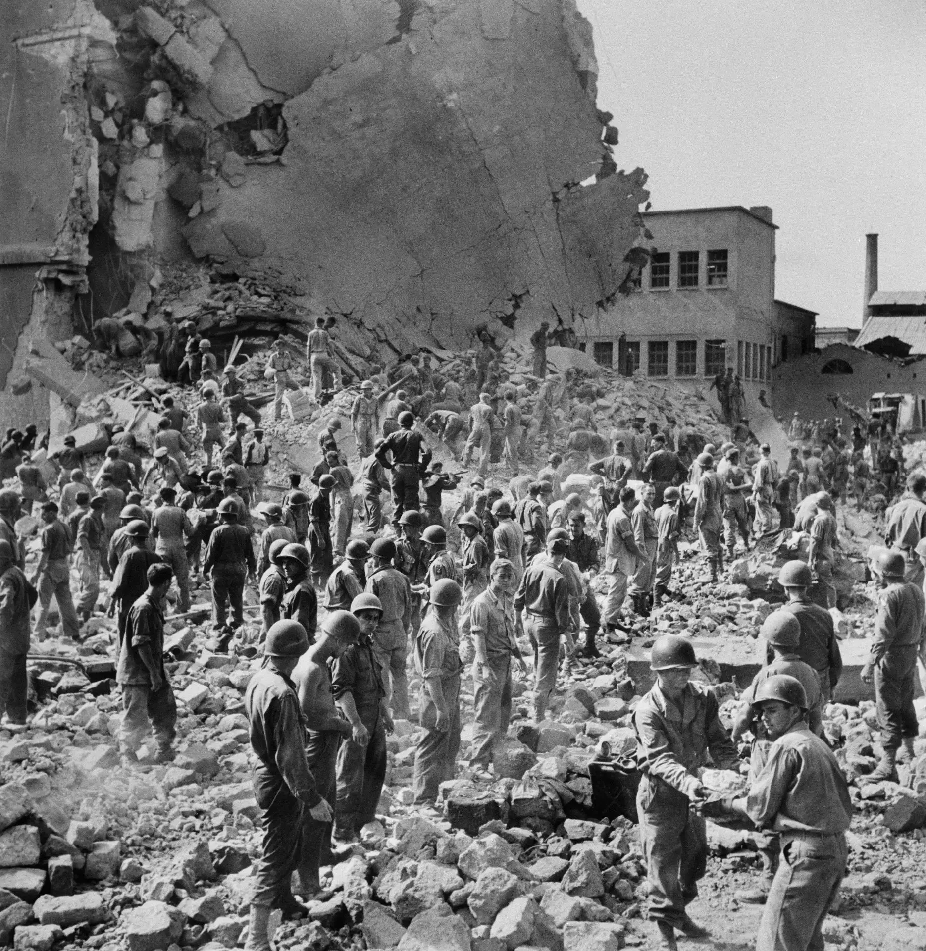 1943. Ряды людей стоят среди руин Центрального почтового отделения, где немцы заложили ...