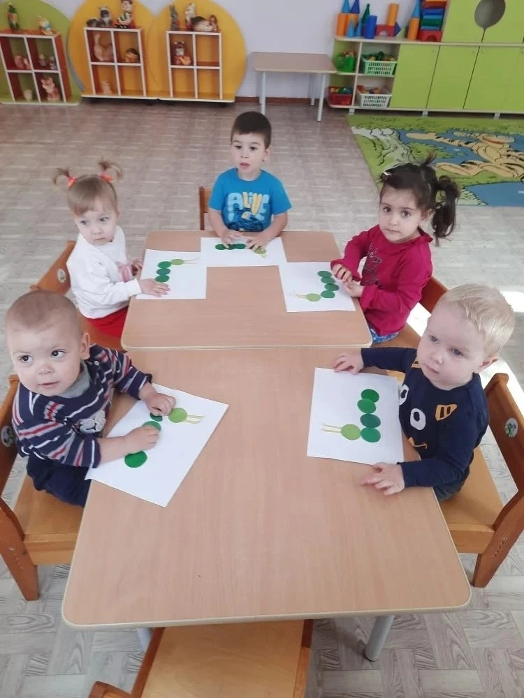 На занятии по аппликации дети младшей группы создали милых гусеничек из зелёных кругов....