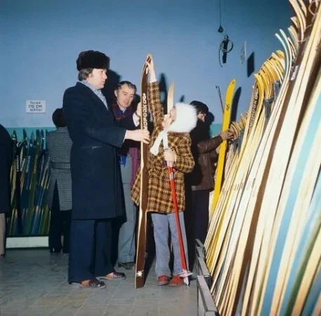 Отец и дочь выбирают лыжи в спортивной секции Детского мира. Москва. 1980