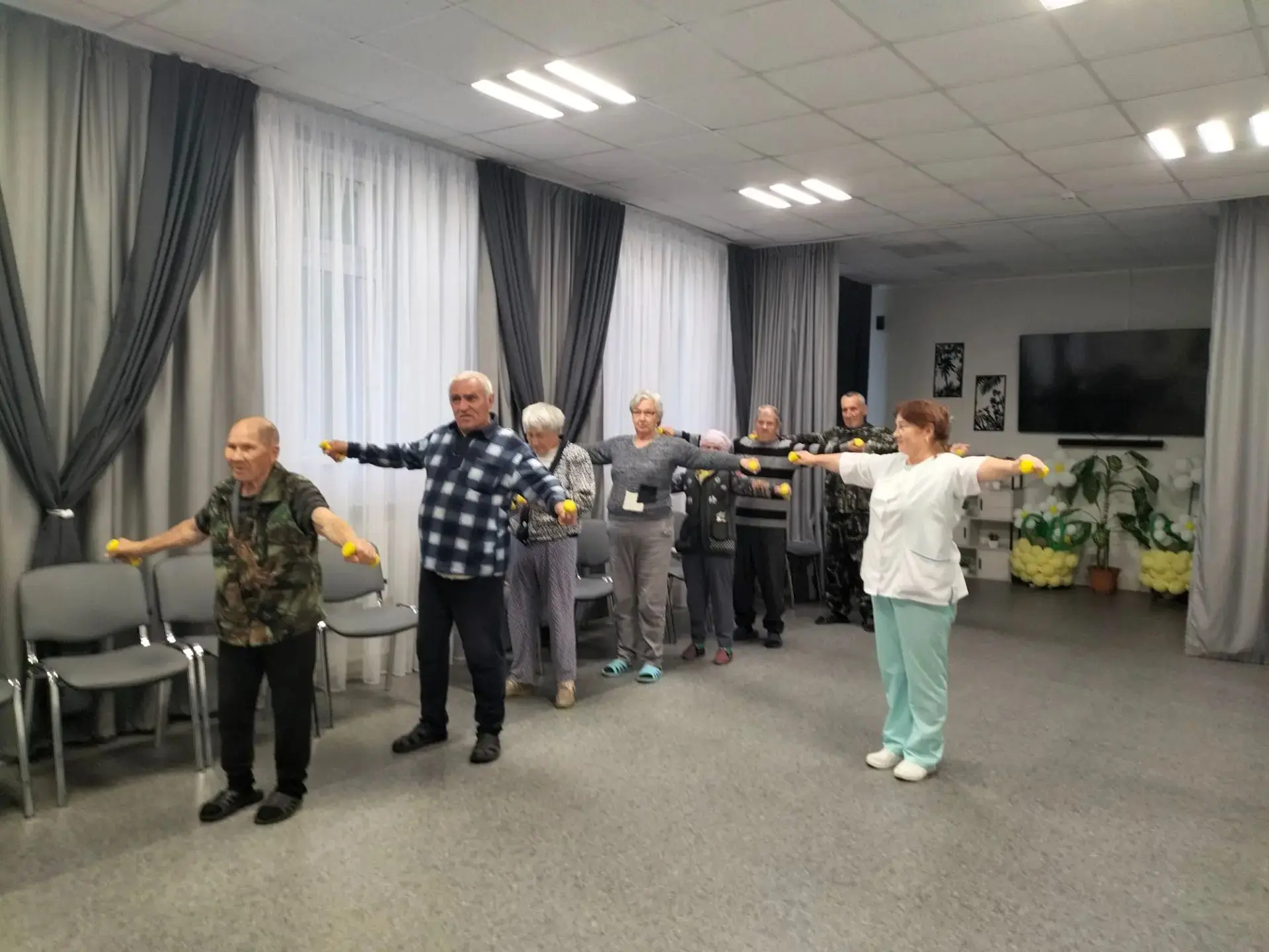 Медицинская сестра провела с подопечными занятие с лёгкими гантелями (0,5–2 кг). В комп...