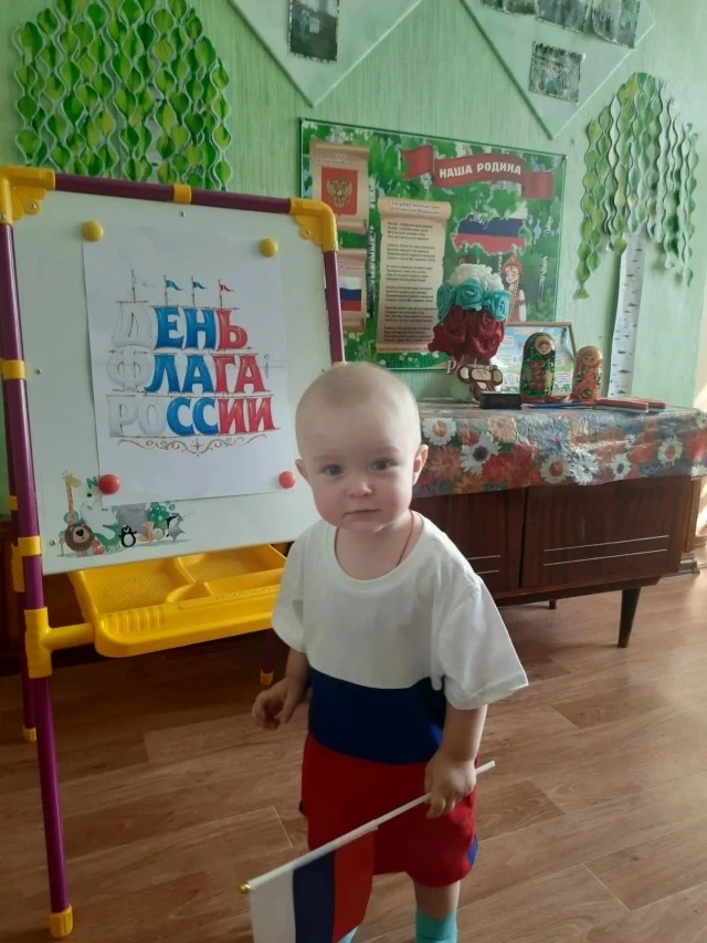 В детских ручках — маленький флажок.