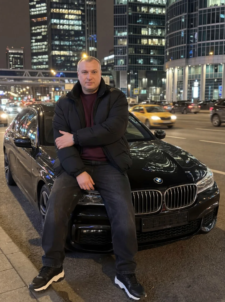 Вечерний драйв 

Мужчина, сидящий на капоте черного bmw ночью в центре оживленного города. Мужчина о