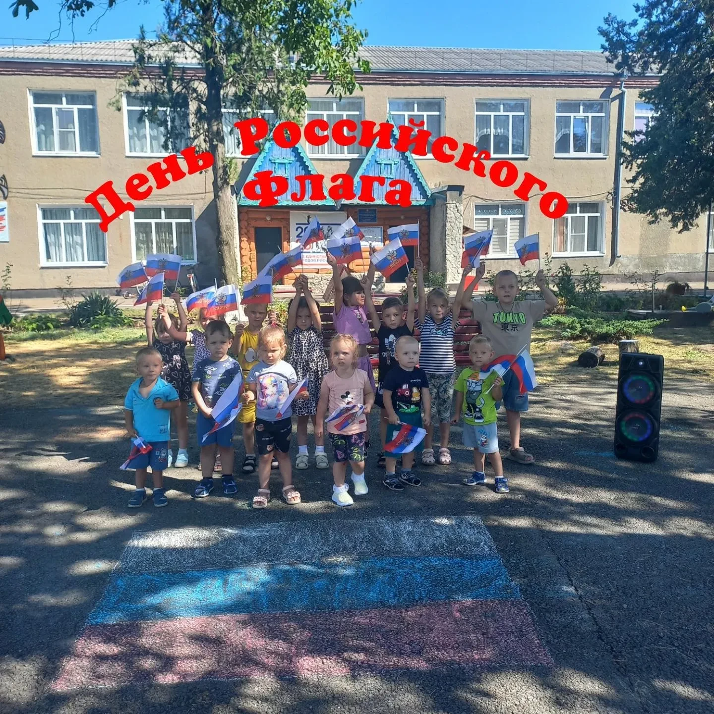 В детских ручках — маленький флажок.