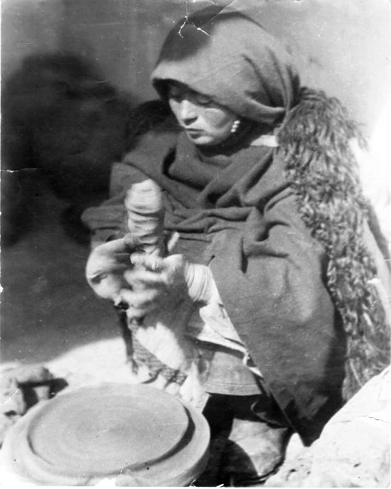 Историческая фотография. Женщина с глиной в руках, сидящая перед гончарным кругом 🔻