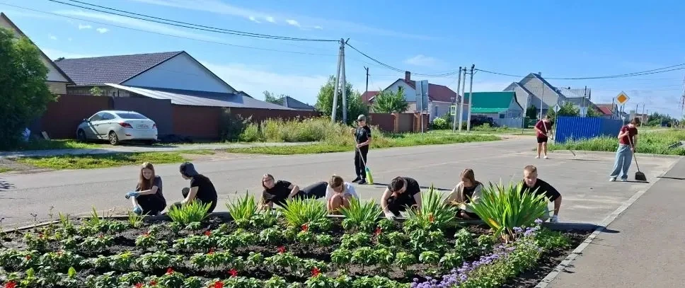 Ребята продолжают трудиться на школьных клумбах, проходят летнюю практику. Они пропалывают сорняки, 