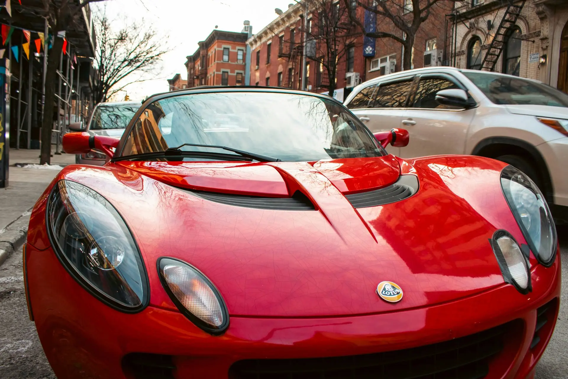 Красный Lotus Elise почти растворяется в ритме бруклинской улицы — низкий силуэт, округ...