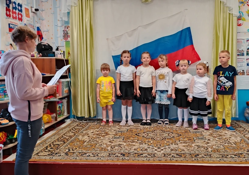 В детских ручках — маленький флажок.