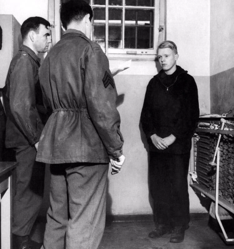 16-летний член Гитлерюгенда К. Пунцеллер слушает американского сержанта, зачитывающий п...
