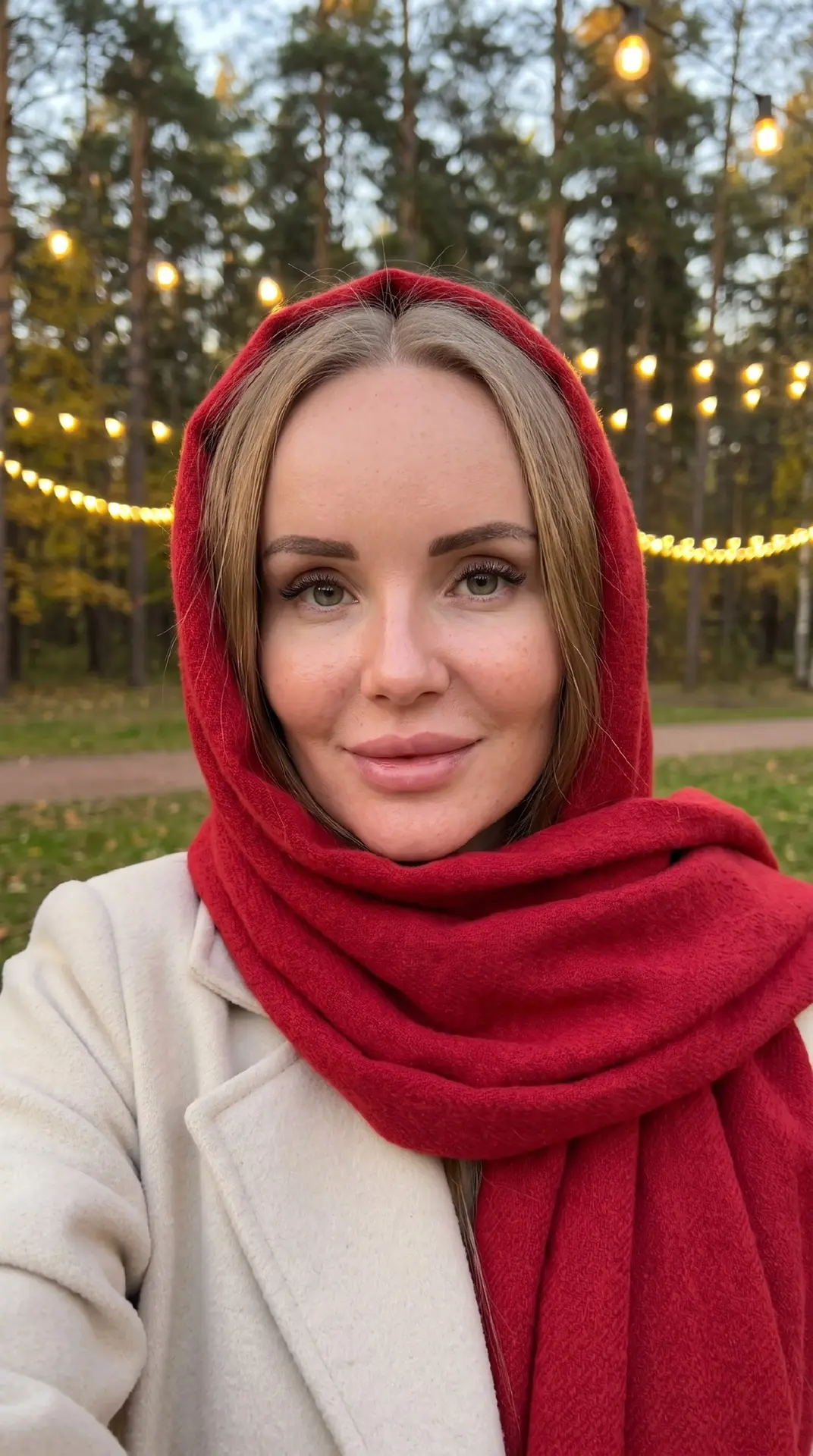 Девушка делает селфи, кисть не видно как будто она держит телефон, стоя в парке осенним...