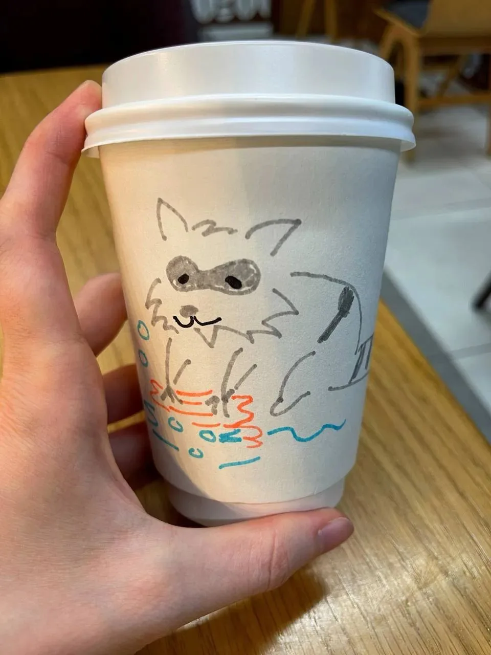 Смотрите, какого милого енотика нарисовали на стаканчике кофе ☕️