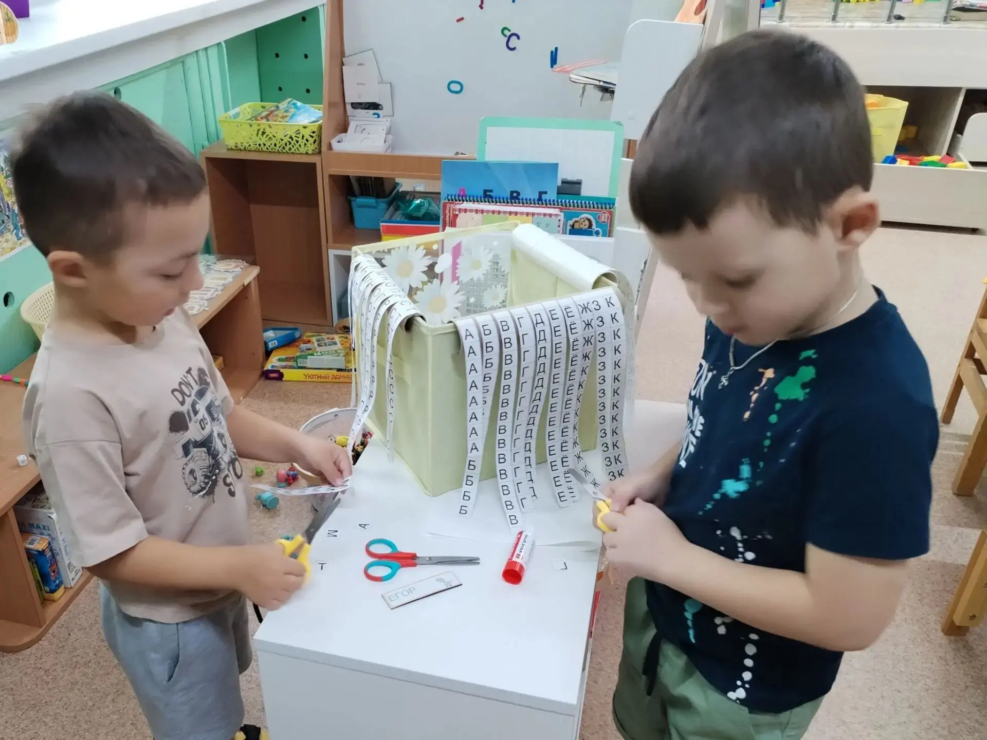 Педагоги из старшей группы Лучики предлагают воспитаникам, подписывая свою работу, испо...